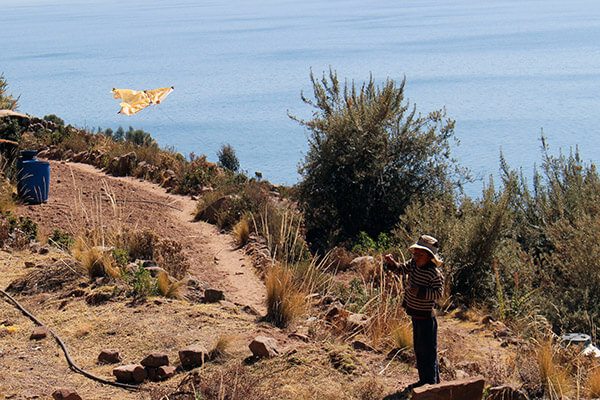 Trip To Peru. Boy flying a kite made from a bag on Taquile Island